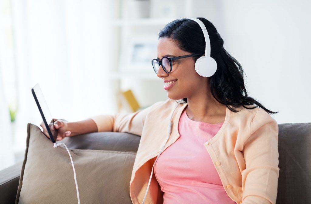 happy woman with tablet pc and headphones at home