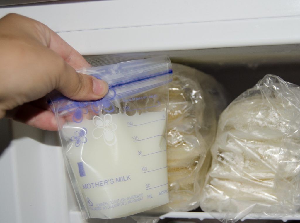 mother putting expressed breast milk in the freezer for storage