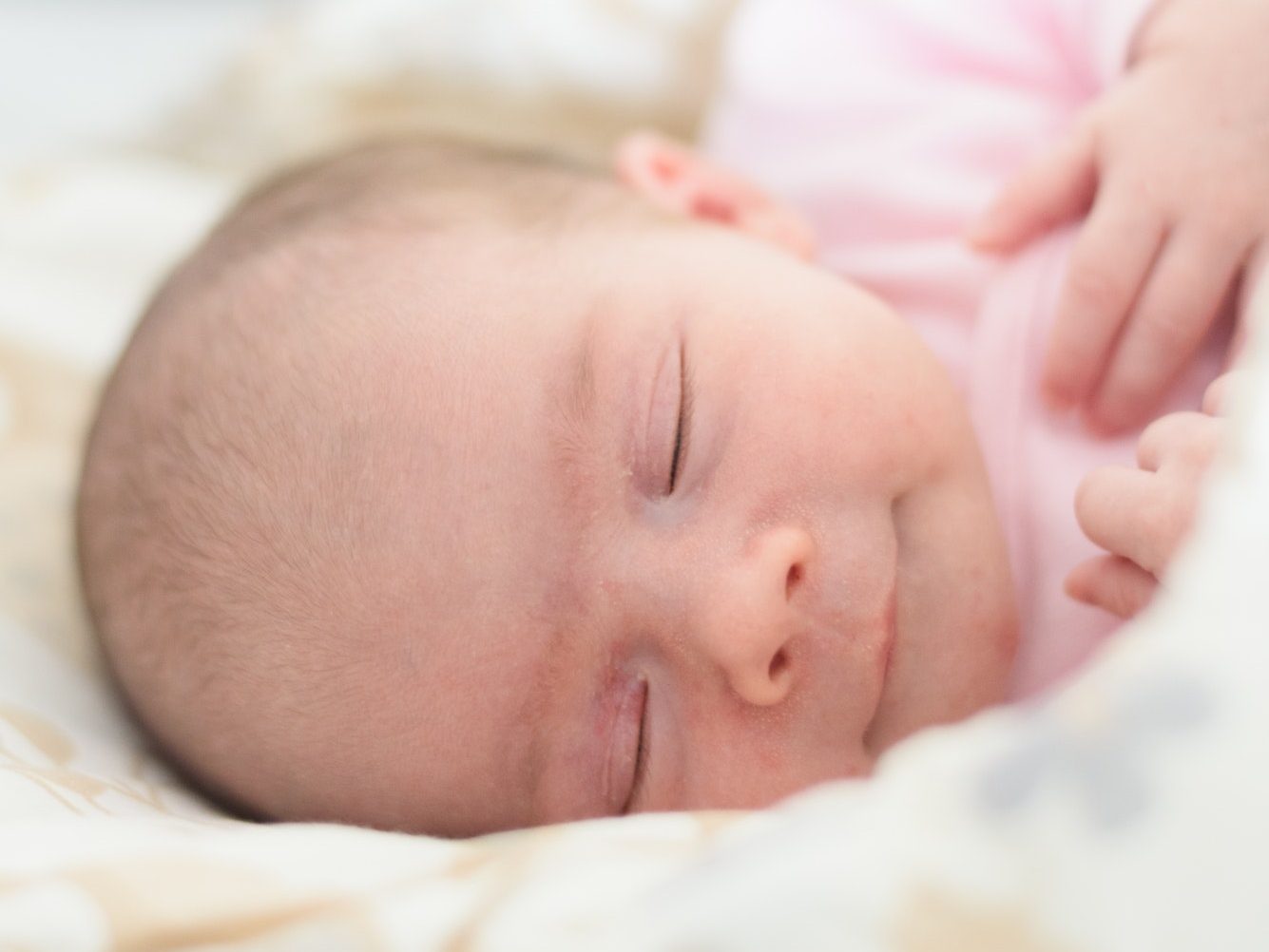 Sleeping newborn baby. Cute little girl one week old. Adorable lying on side covered with blanket.