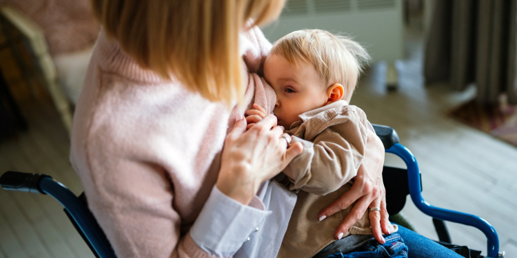 Young mother with disability in wheelchair breast feeding her child at home