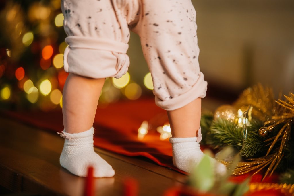 Cute little baby legs in room with Christmas tree