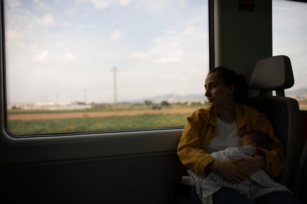 Young girl discretely breastfeeding her baby on the train