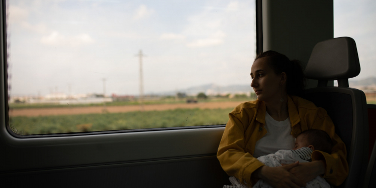 Young girl discretely breastfeeding her baby on the train