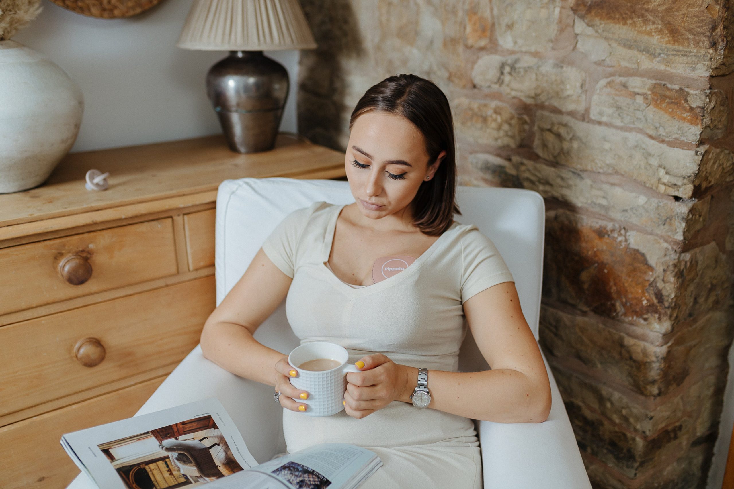 Mother using Pippeta breast pump as she drinks tea and reads a magazine