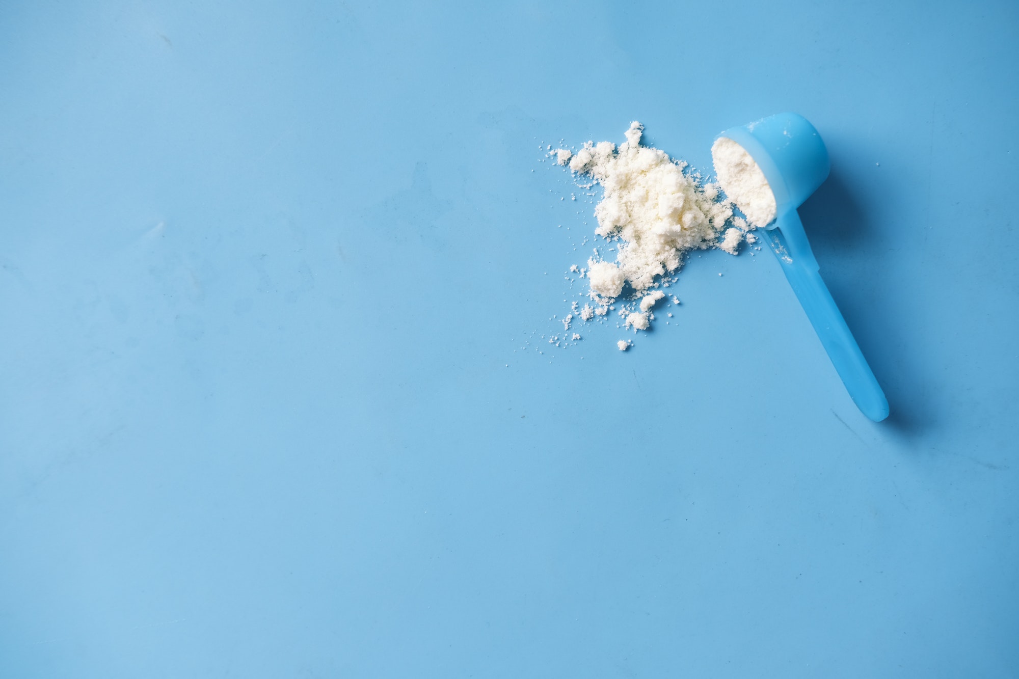 baby milk powder and spoon on blue background.