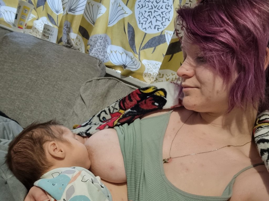 Mother at home on sofa breastfeeding newborn