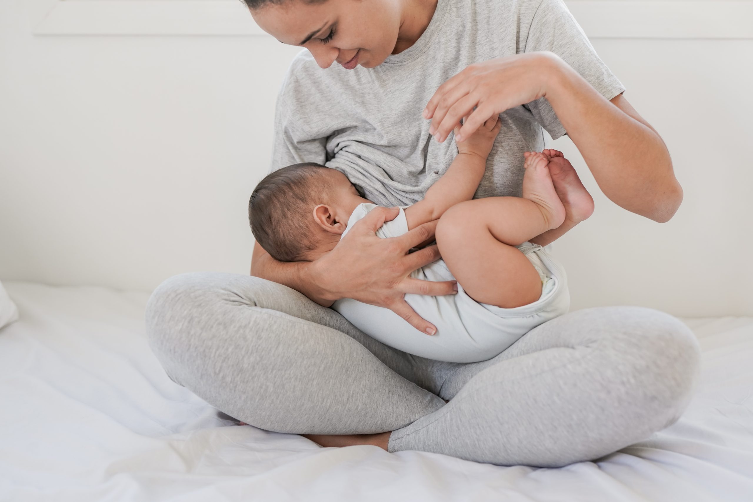 mother dressed in grey breastfeeding infant