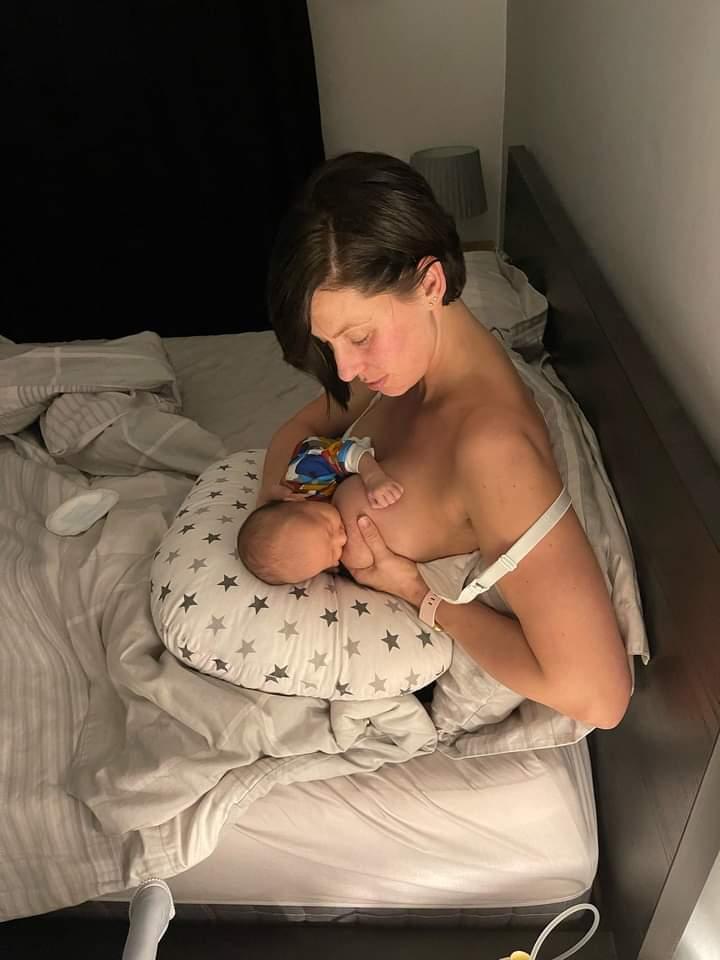 Breastfeeding mother using feeding pillow to breastfed newborn baby in bed