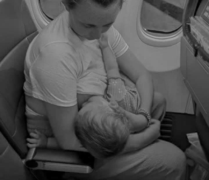 Black and white photo of mother breastfeeding on a plane