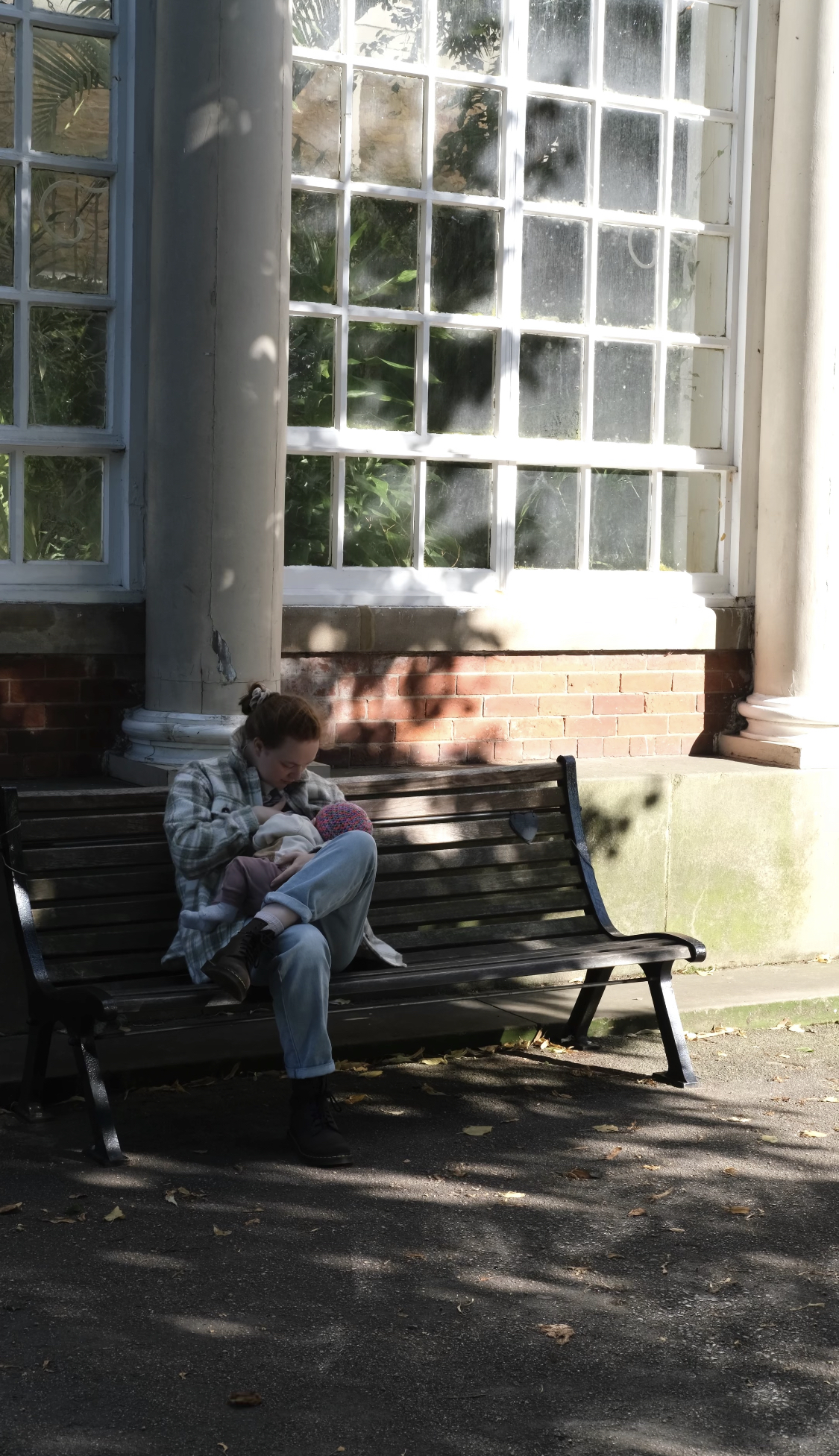Alice breastfeeding her baby outside on a bench