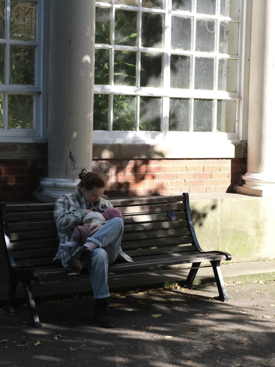 Alice breastfeeding her baby outside on a bench