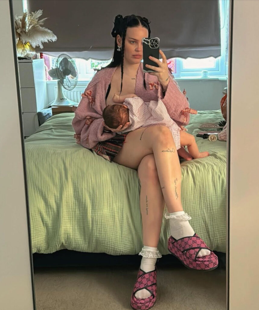 Anne Marie breastfeeds her newborn atop bed