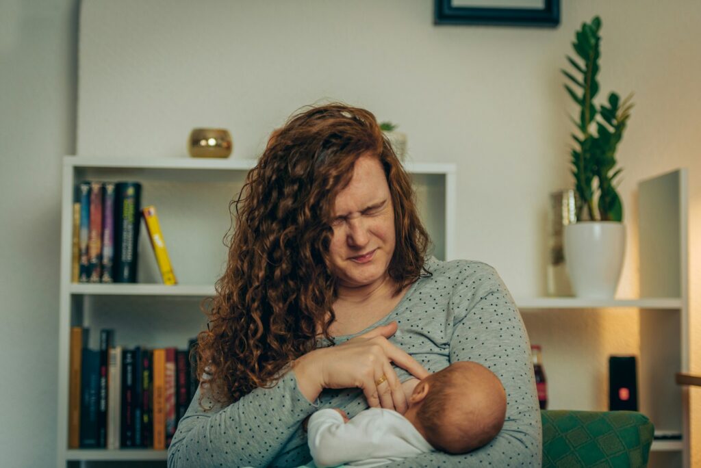 Mother in pain breastfeeding baby