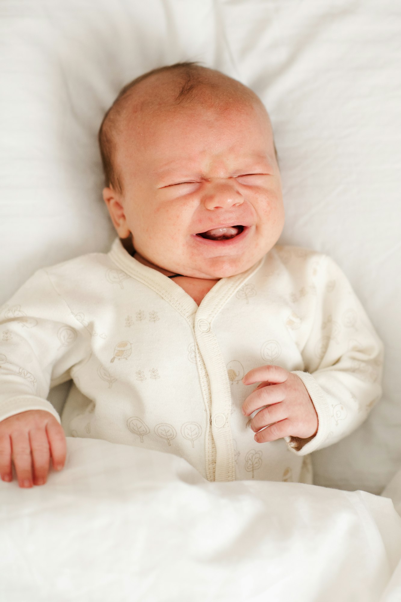 Sick baby crying with colic pain in bed