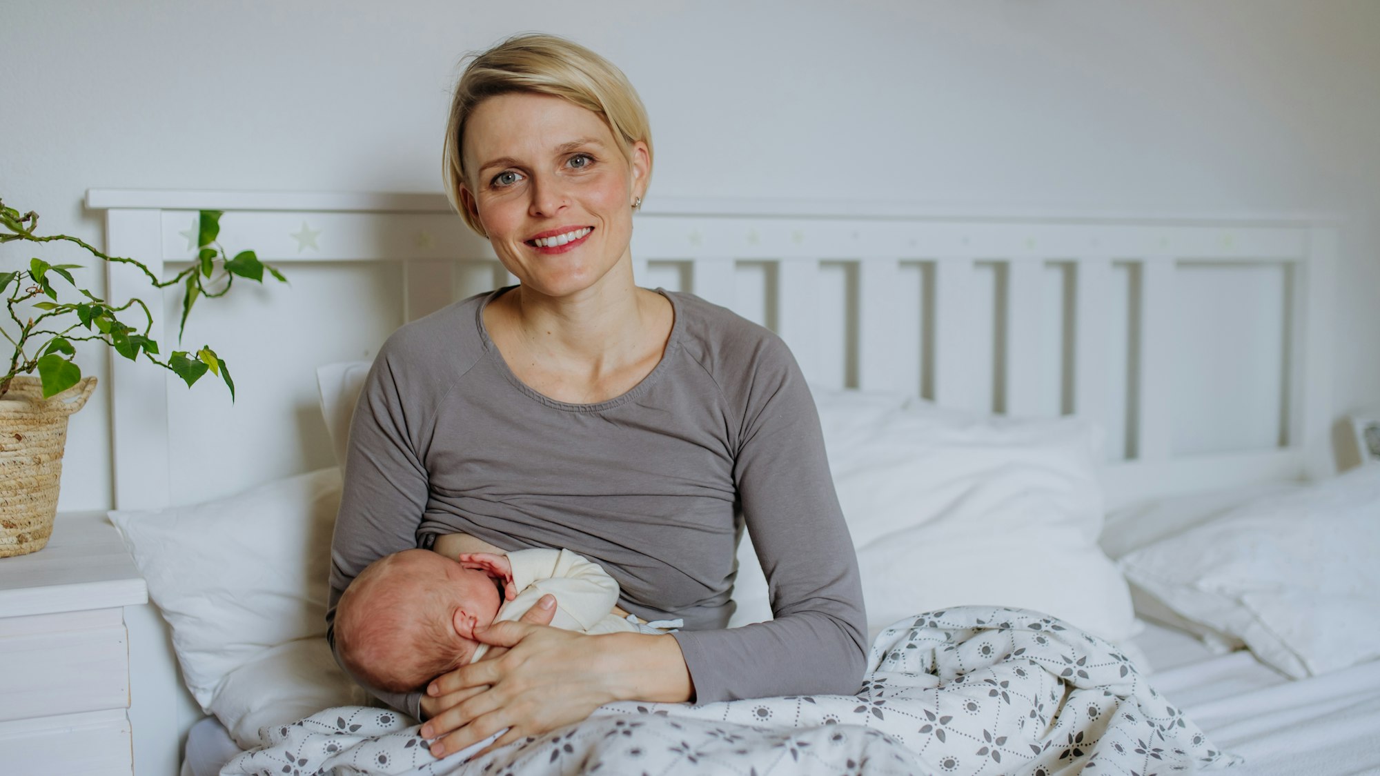 Mother brestfeeding her little newborn baby in their bedrooom.