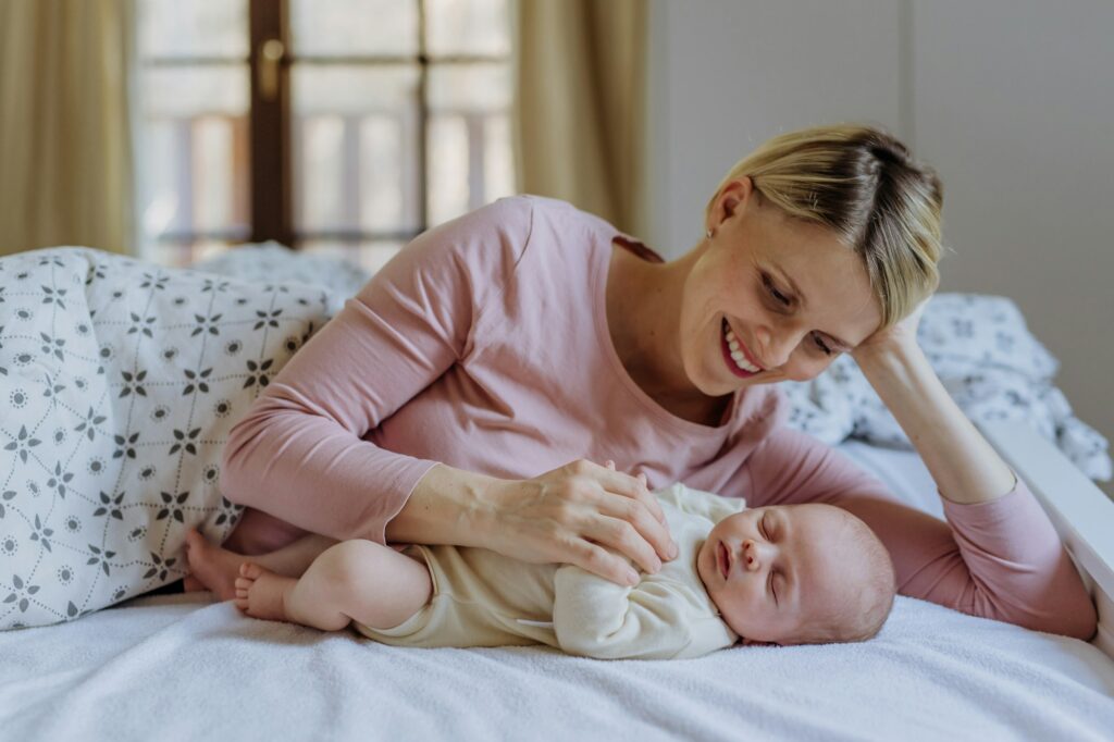 Mother cuddling with her newborn baby in their bad.