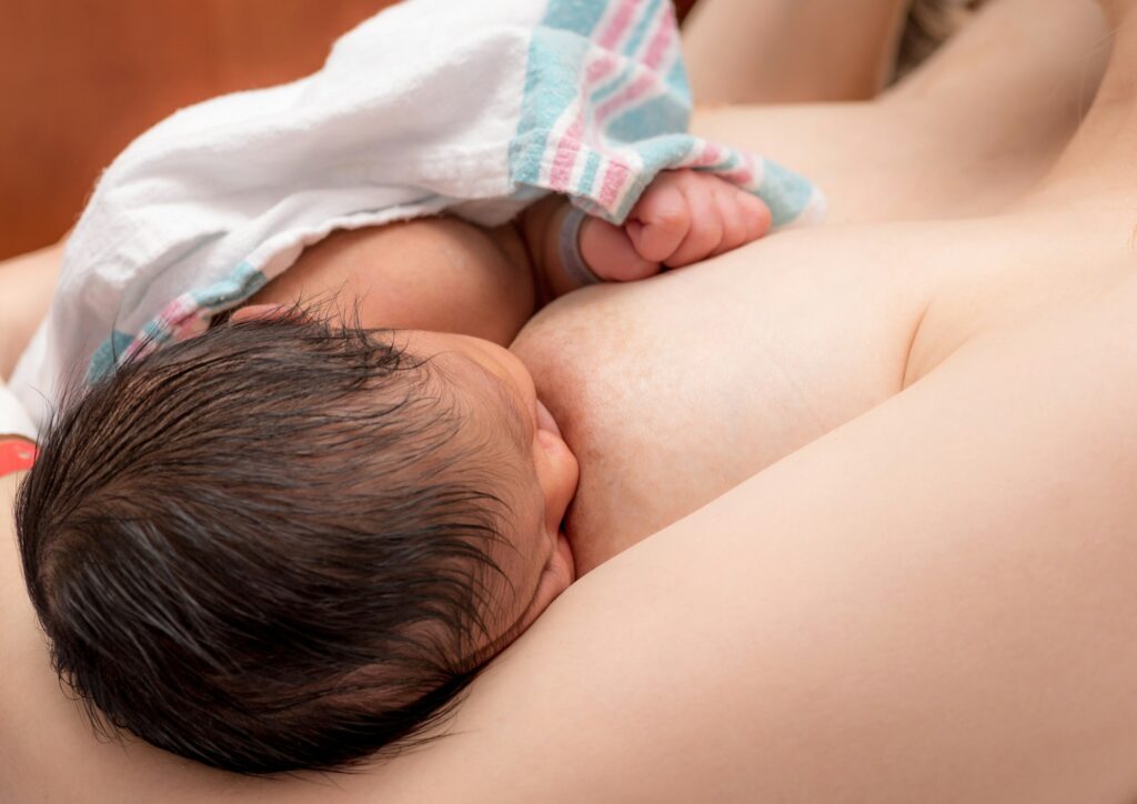 Mother in hospital breast feeding newborn diverse baby baby