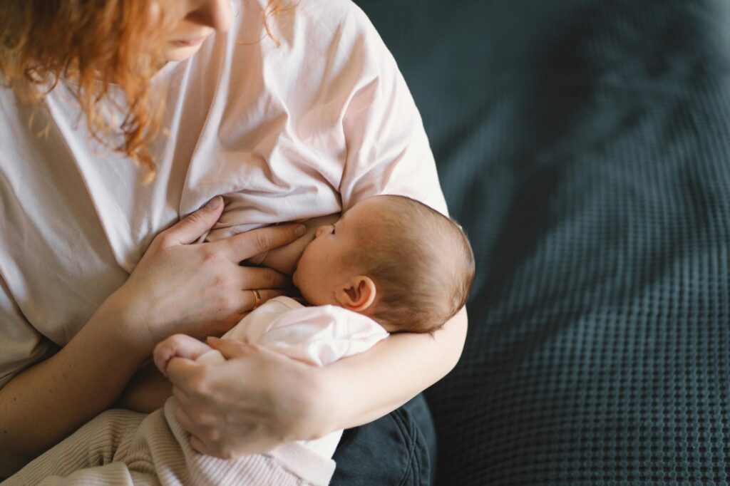 Newborn baby girl sucking milk from mothers breast.