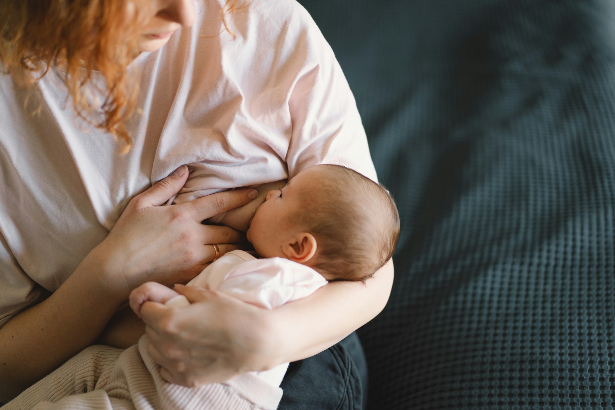 Newborn baby girl sucking milk from mothers breast.