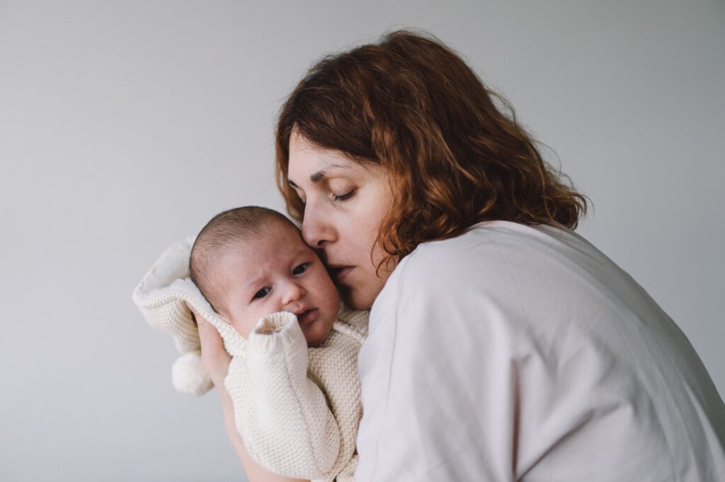 Portrait of happy mum holding infant child on hands.