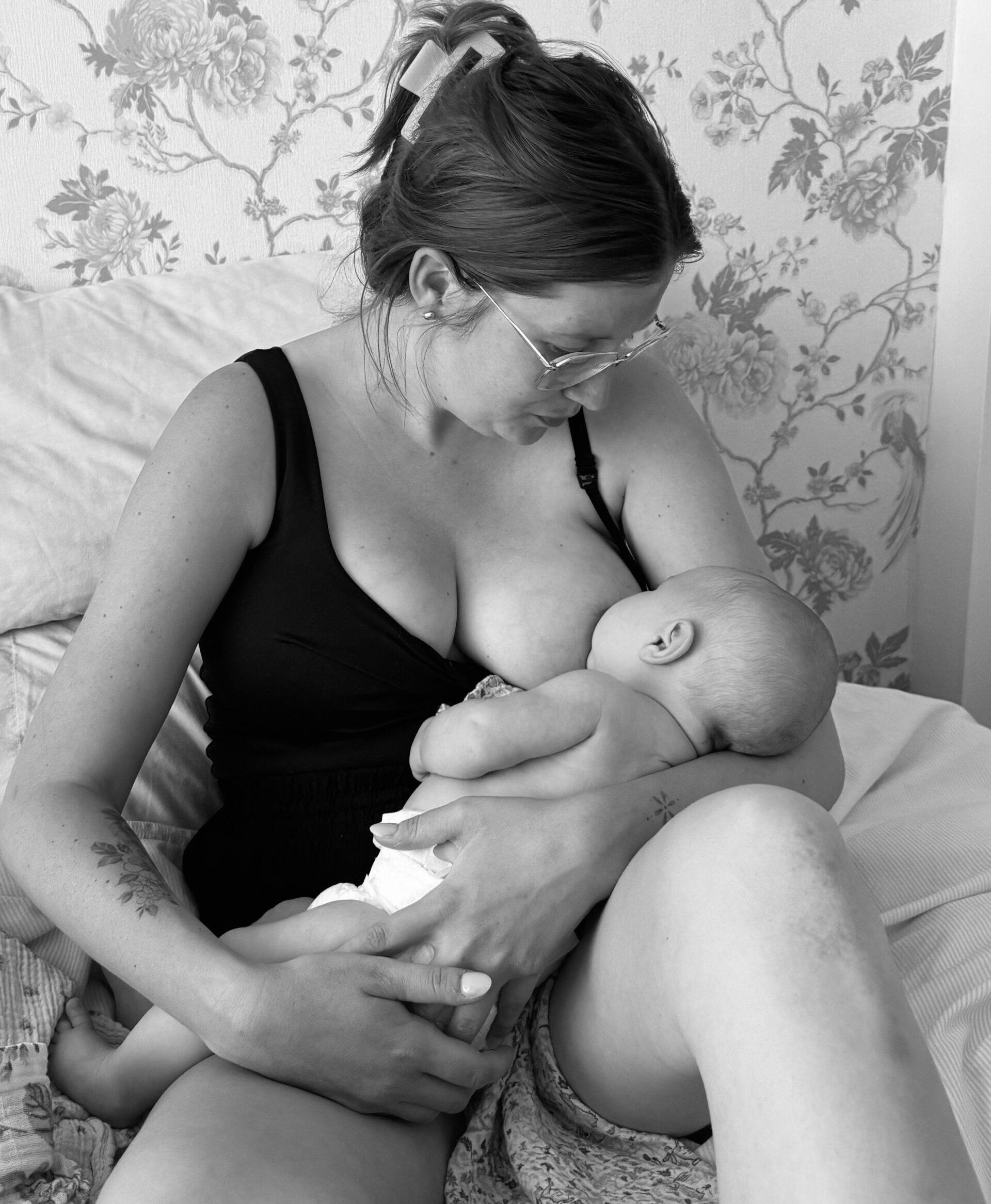 Megan breastfeeding baby daughter on bed