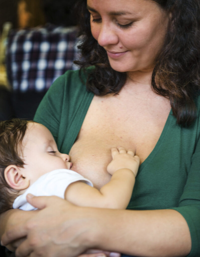 mother wearing green top, breastfeeding infant