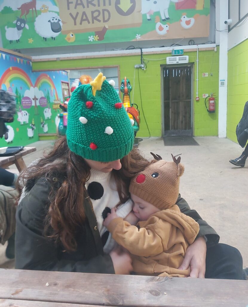 Grace breastfeeding son, wearing Christmas hats