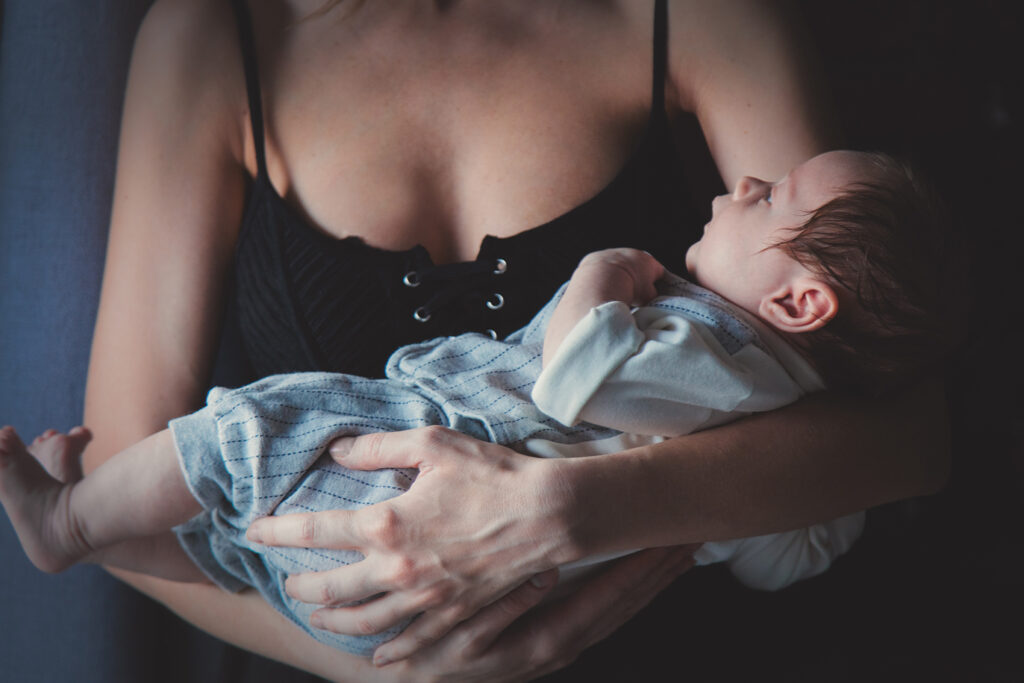 woman holding infant baby in her arms, close to her chest