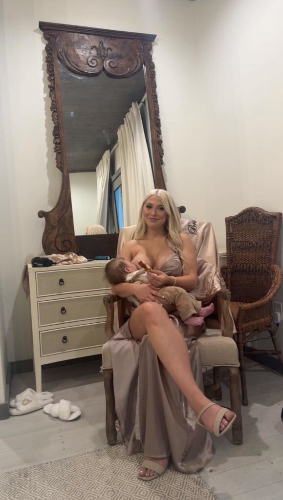 Jade wearing a bridesmaid outfit and breastfeeding her son 