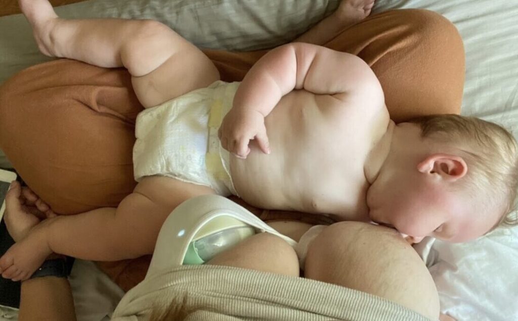 Image of baby breastfeeding whilst mother uses wearable breast pump
